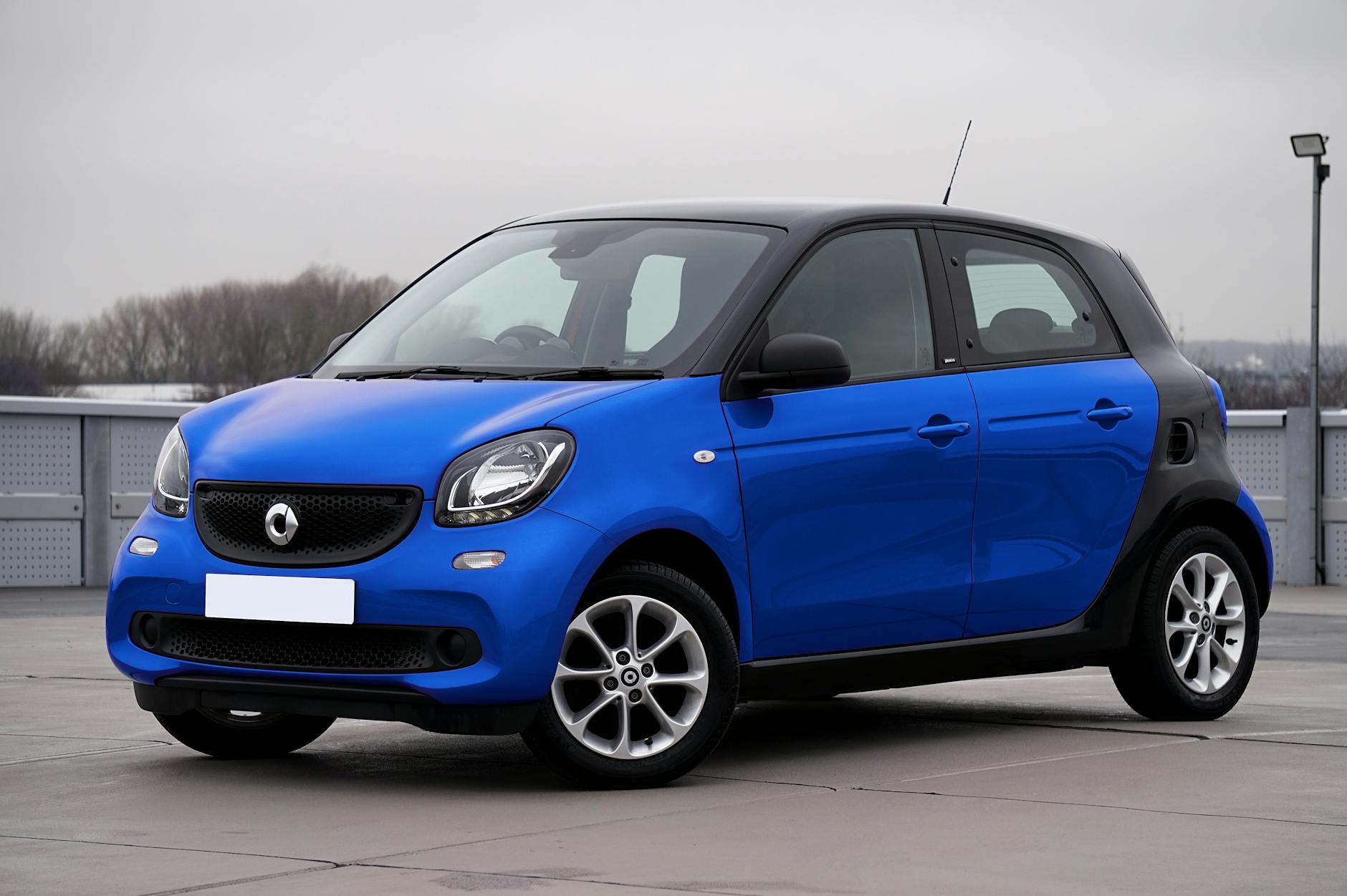 Niebieski Smart Forfour zaparkowany na ulicy w miejskiej zabudowie