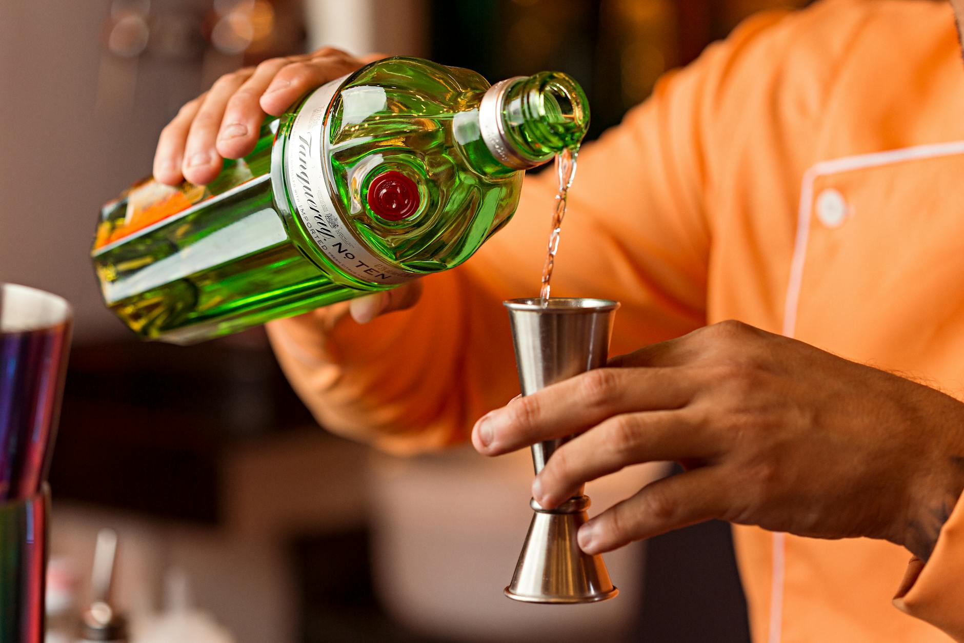 Barman nalewa gin do jiggera, przygotowując drinka