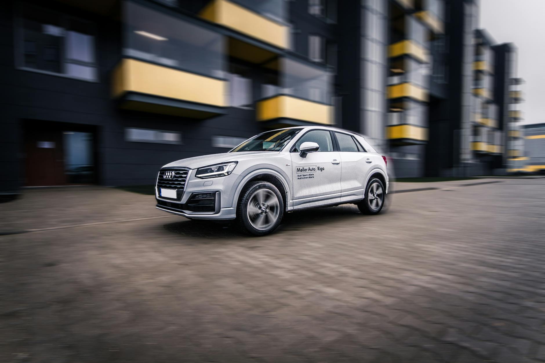 Nowoczesny SUV Audi w ruchu na tle wieczornej panoramy miasta