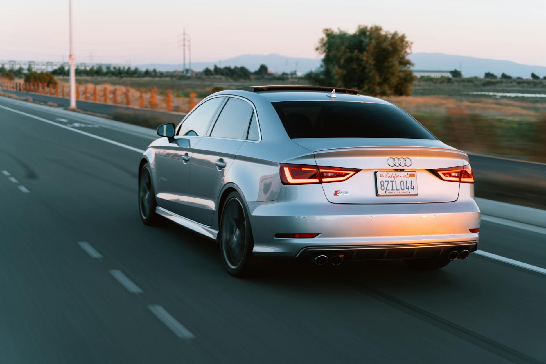 Srebrna Mazda 6 jedzie pustą szosą o zachodzie słońca