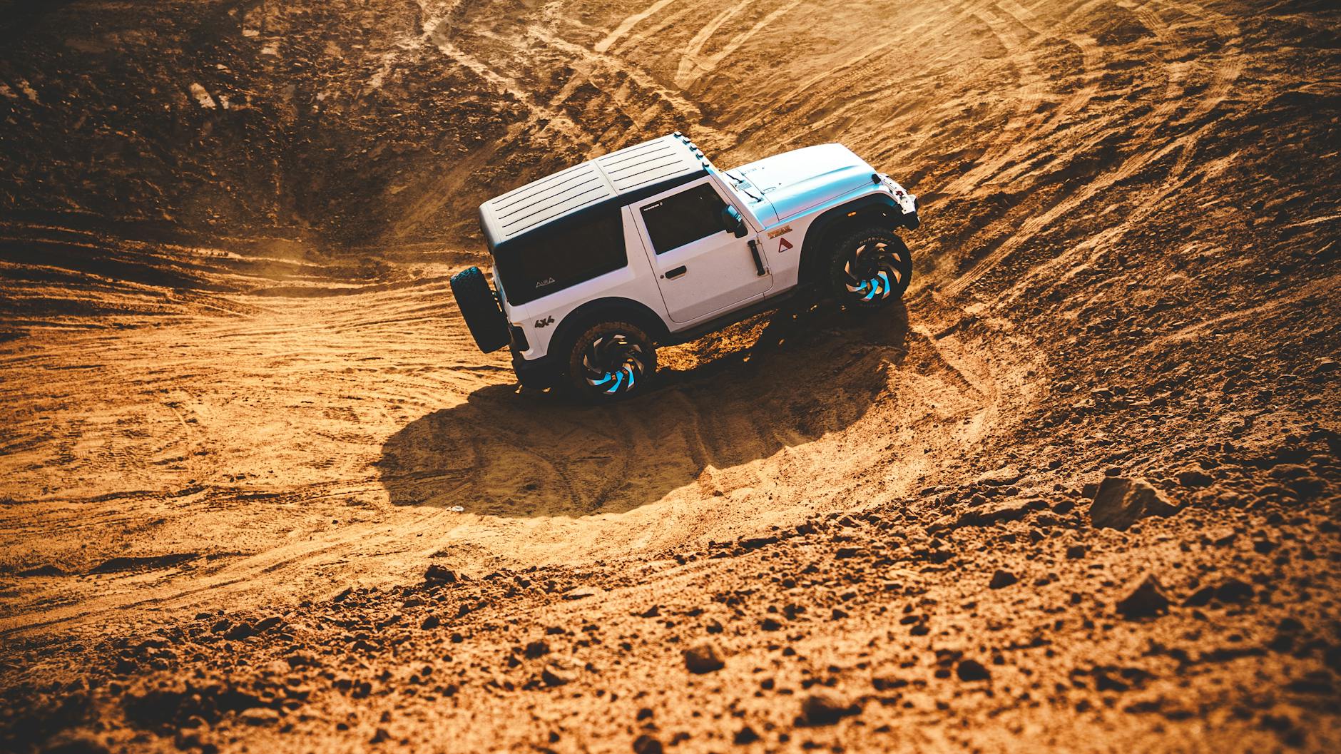 SUV jedzie dynamicznie po piaszczystych wydmach, pokazując napęd 4x4