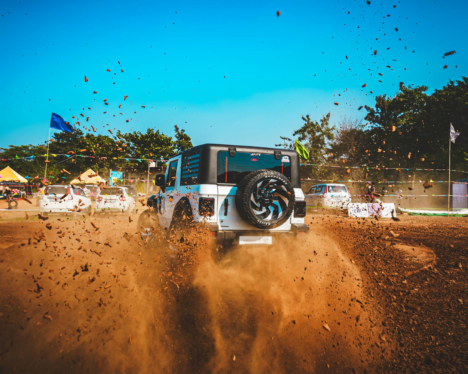 SUV jedzie po zakurzonej, terenowej drodze w trakcie offroadu