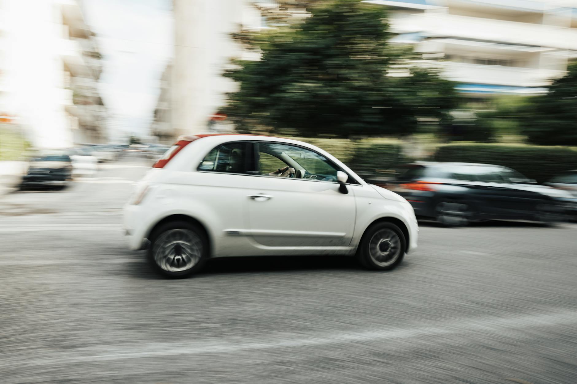 Białe Mitsubishi Colt pędzi po miejskiej ulicy z rozmytym tłem