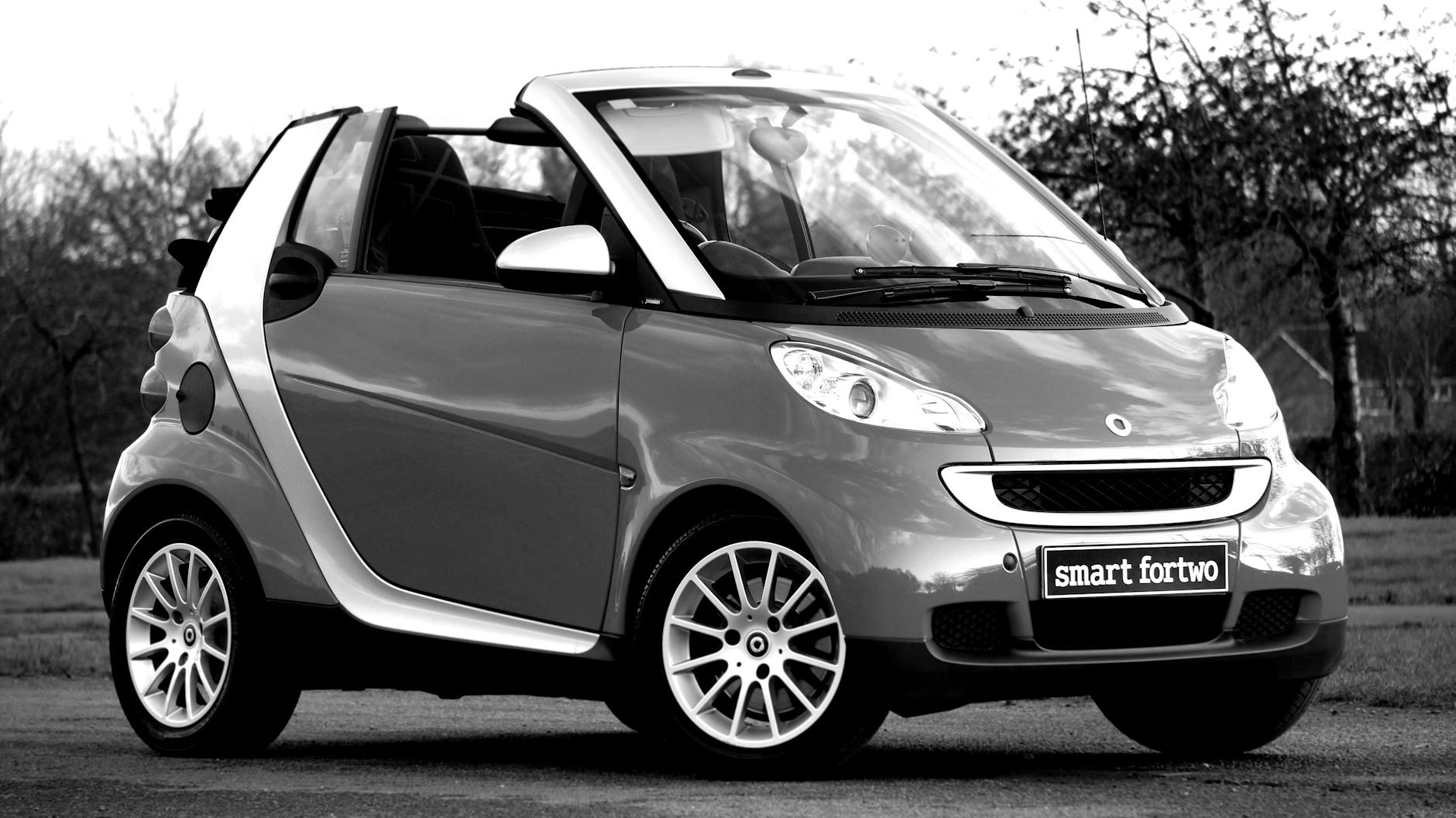 Czarno-białe zdjęcie klasycznego kabrioleta Smart Fortwo na ulicy