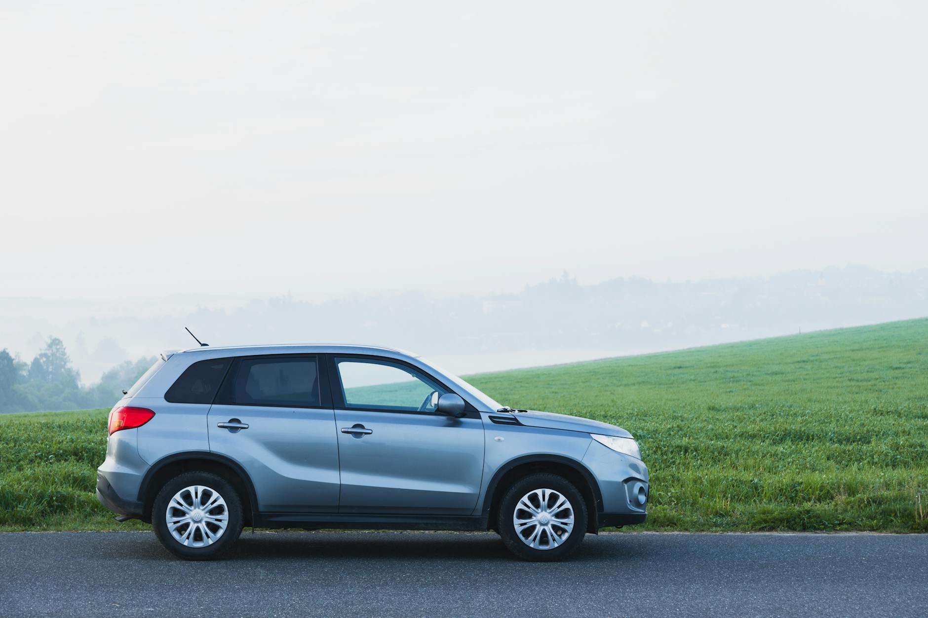 Srebrny SUV Geely na mglistiej wiejskiej drodze w Czechach Srebrny SUV Geely na mglistiej wiejskiej drodze w Czechach