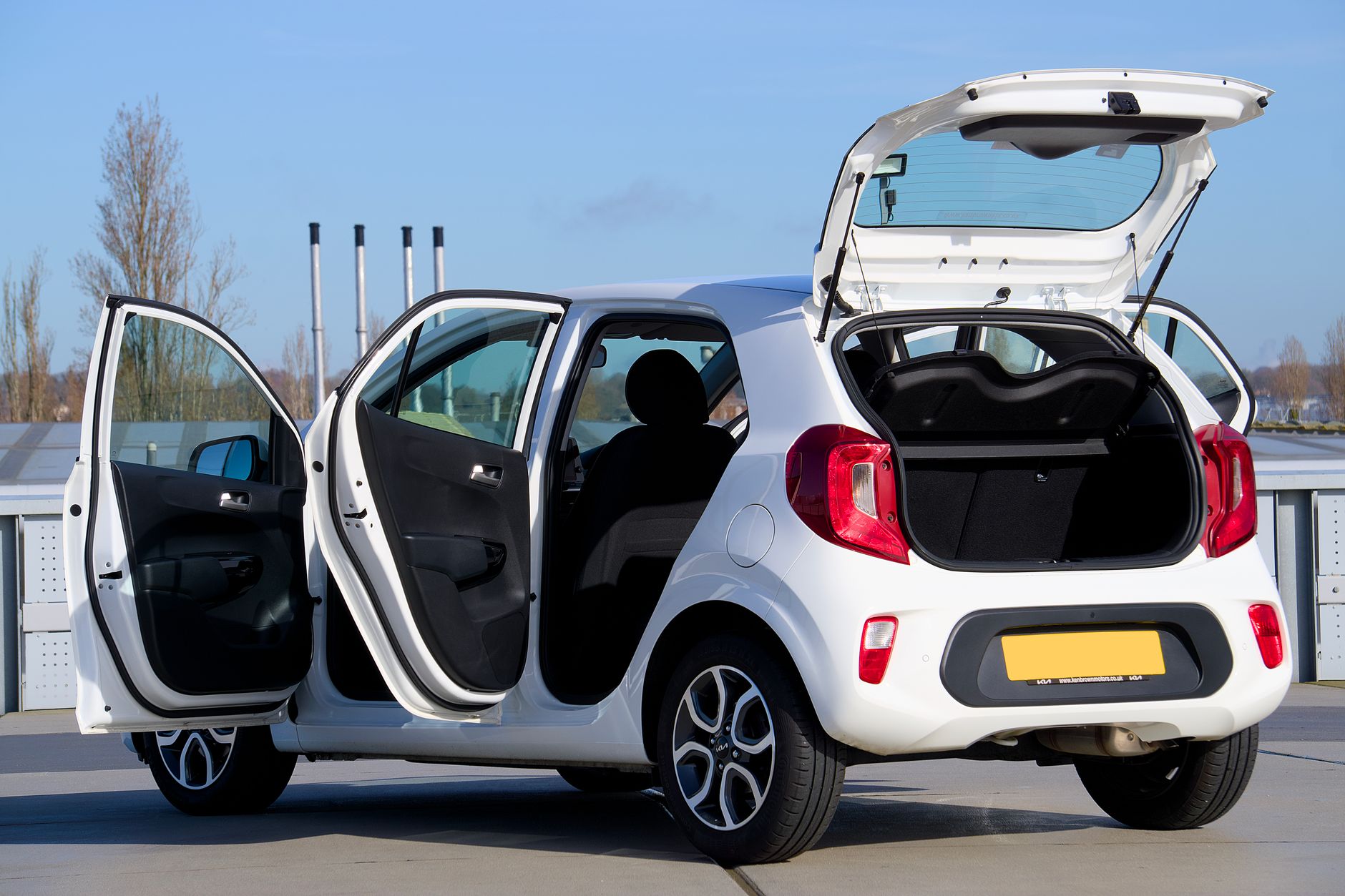 Citroën C3 jako pierwsze auto miejskie: zalety, wady i koszty Biały Citroën C3 z otwartymi drzwiami i bagażnikiem na ulicy miasta