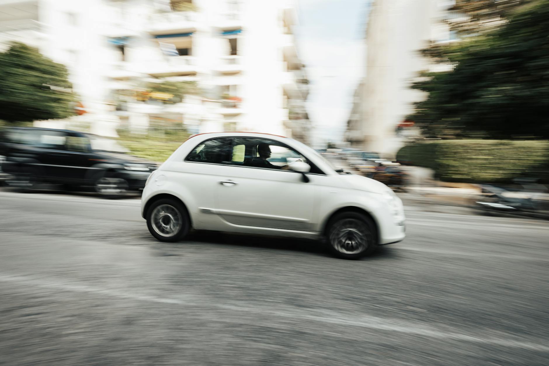 Biały miejski Citroën jedzie dynamicznie ulicą w centrum miasta