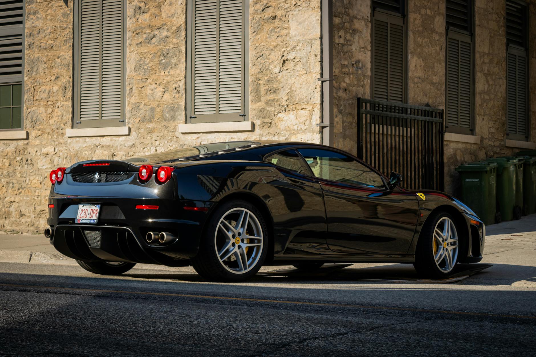 Czarne Ferrari zaparkowane przy kamiennym budynku w centrum miasta