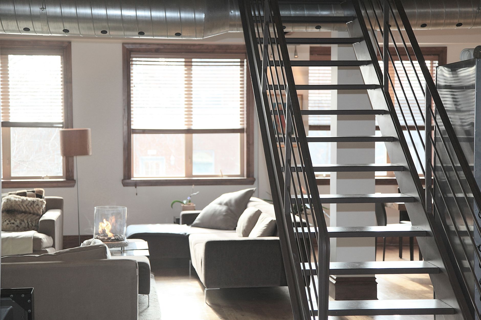 Jasny loftowy salon z wygodną sofą i industrialnymi lampami