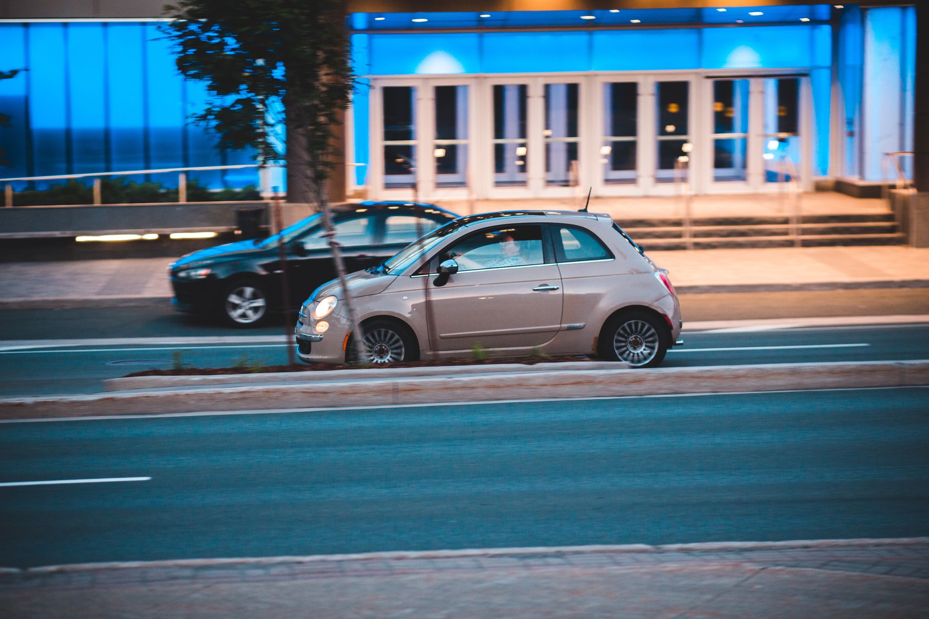 Citroën C1, C2 czy C3: który mały Citroën najlepiej znosi jazdę po mieście Mały samochód miejski jedzie nocą obok nowoczesnego podświetlonego budynku