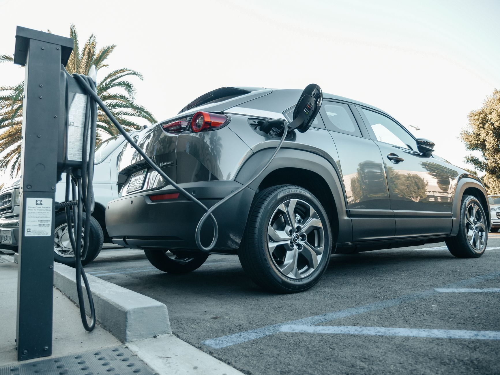 Elektryczny SUV ładowany na zewnętrznej stacji w dzień Elektryczny SUV ładowany na zewnętrznej stacji w dzień