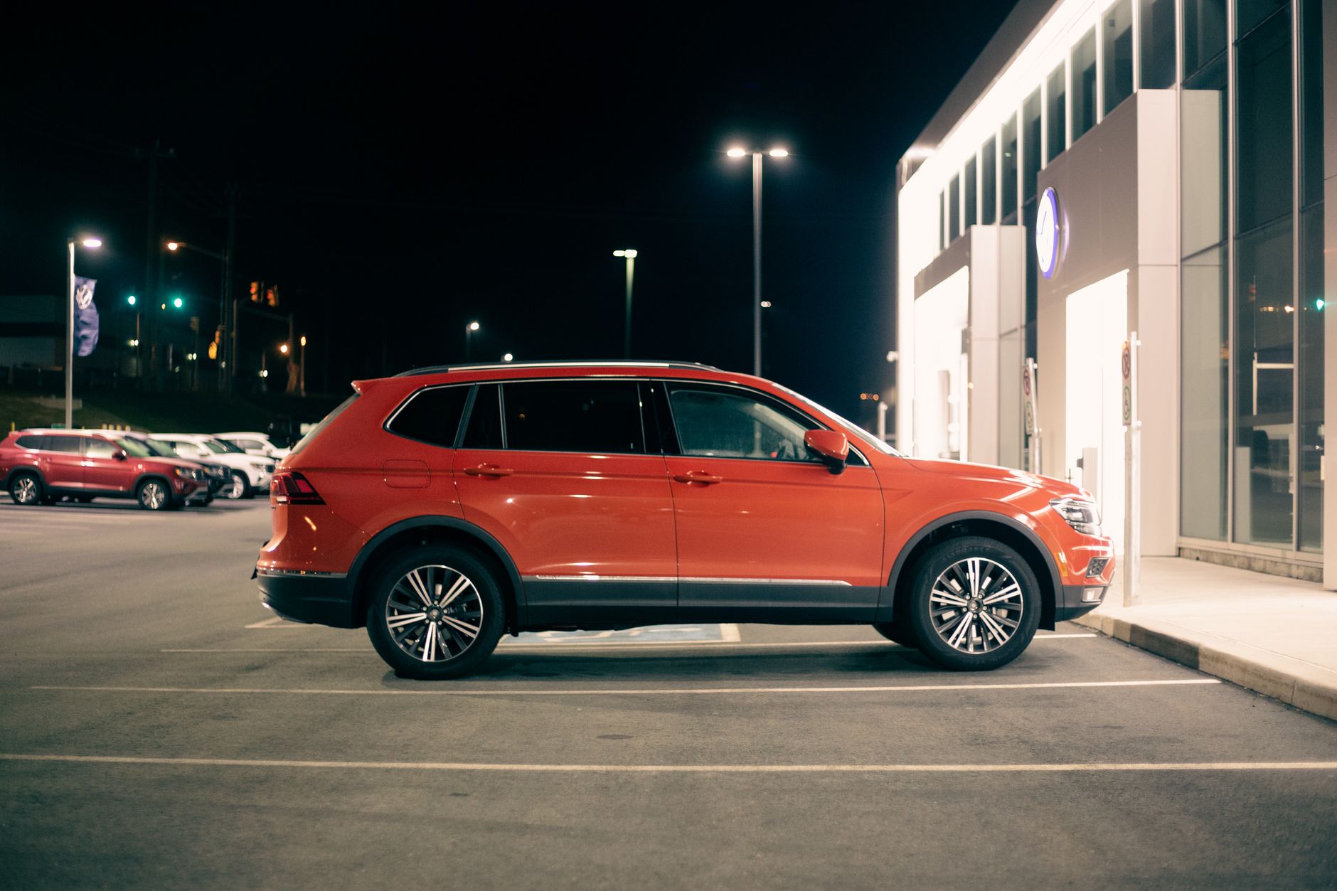 Czerwony luksusowy SUV zaparkowany nocą przy wejściu do sklepu