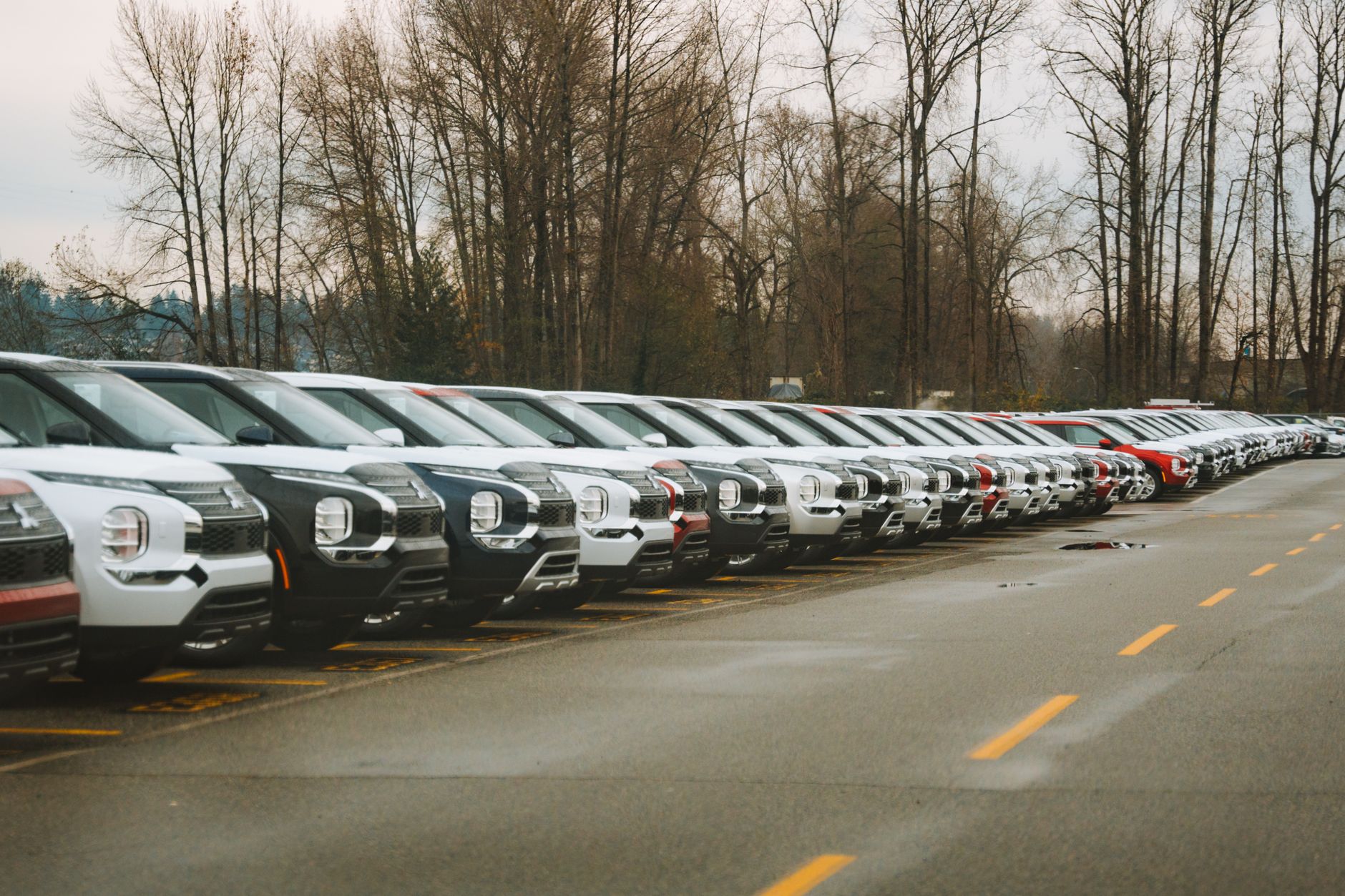 Rząd nowych SUV-ów na parkingu pod chmurnym niebem