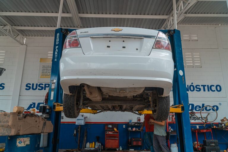 Biały Chevrolet uniesiony na podnośniku w warsztacie samochodowym