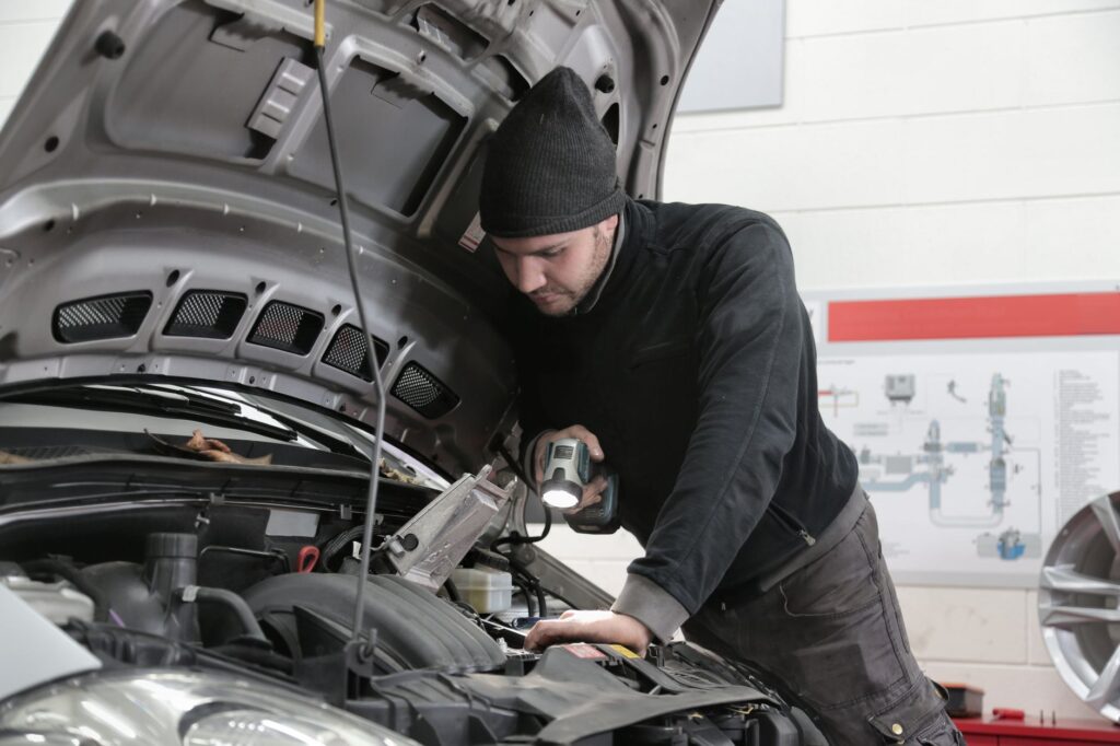 Mechanik z latarką sprawdza silnik samochodu w garażu