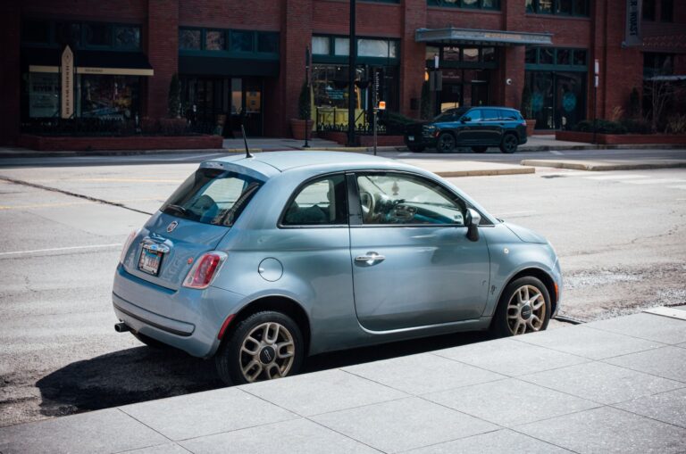 Niebieski Fiat 500 zaparkowany na ulicy w Chicago na tle ceglanego budynku